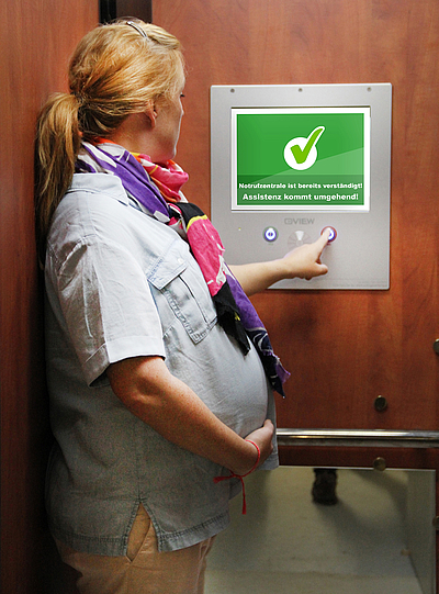 Schwangere Frau bedient in einem Aufzug das View-Display. Foto: View Promotion